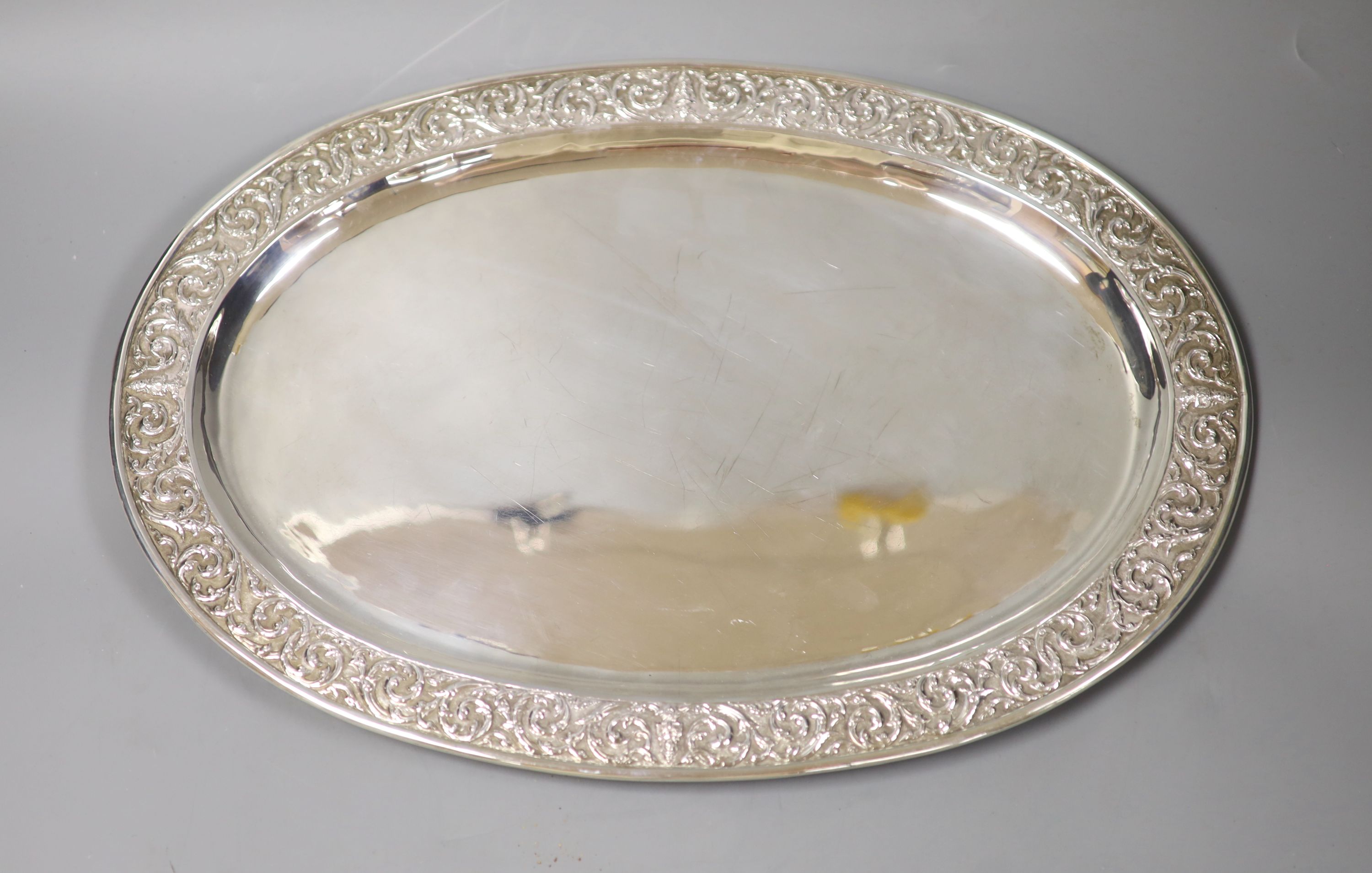 A Thai Sterling white metal oval dish with repousse decoration on four stud feet,